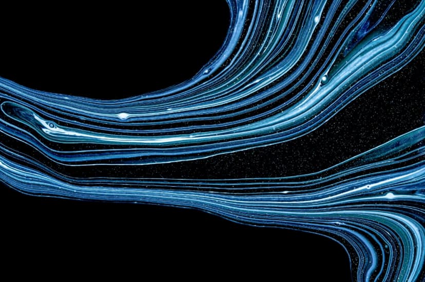 Abstract image of flowing blue and white marbled streaks sweeping across a black background speckled like stars.