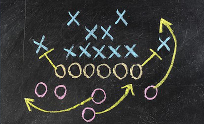 Chalkboard football play diagram with Xs and Os connected by arrows showing planned player movement.