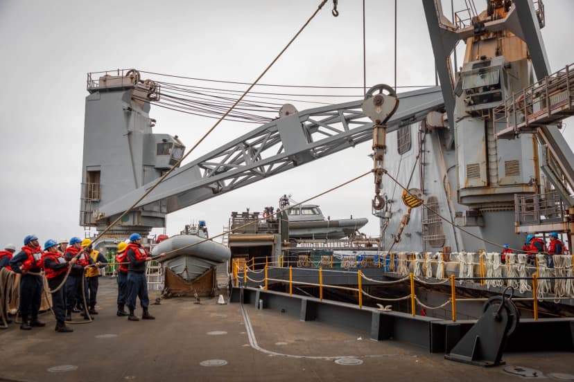 Crane operations with sailors holding ropes