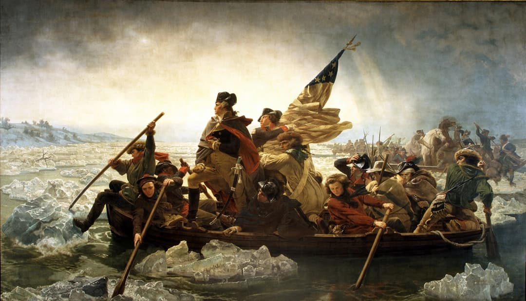Iconic painting of George Washington crossing the Delaware River during the American Revolution. Washington stands at the front of a small boat, holding a telescope and flanked by soldiers rowing through icy waters under a dramatic sky. An American flag billows behind him, while troops and artillery cross in the background, capturing a pivotal moment of determination and resolve.