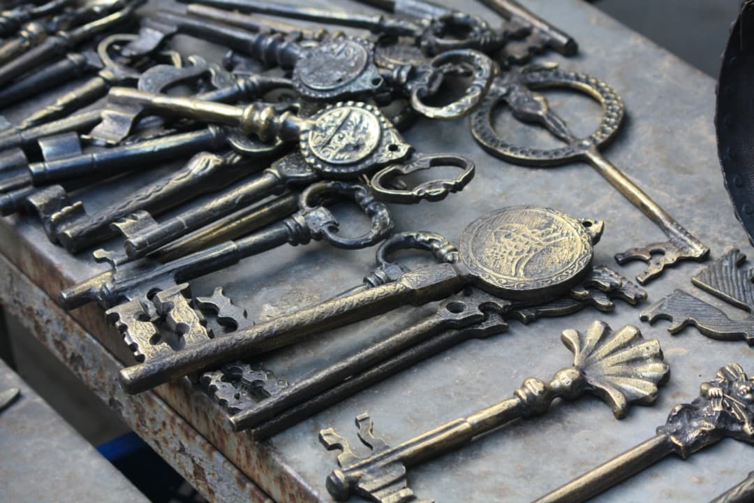 Assortment of ornate vintage keys laid out on a metal surface.