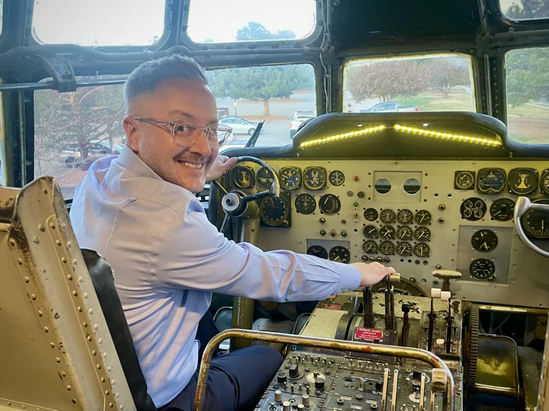 Jeff Thomas sits in the cockpit of a vintage KC-97 refueling aircraft, smiling while posing at the controls inside The Airplane Restaurant in Colorado Springs.