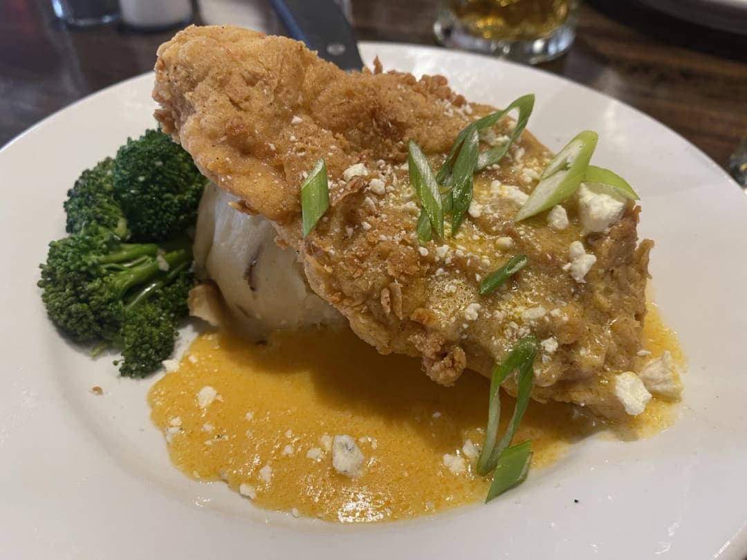 Plate of Lemon Tabasco Fried Chicken served over mashed potatoes with a side of steamed broccoli, topped with crumbled cheese and green onions at Phantom Canyon Brewing Co.