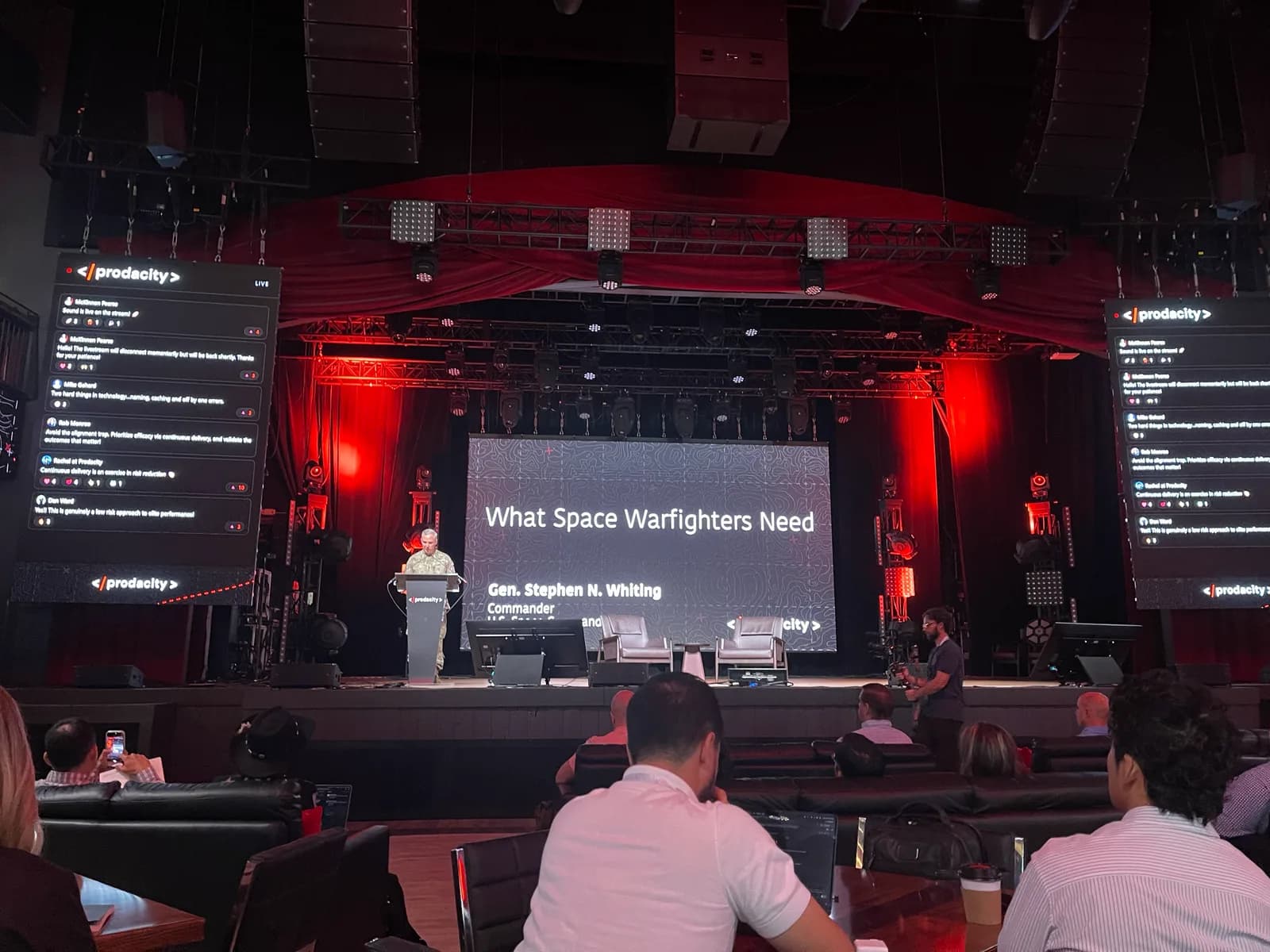 Prodacity main stage, a uniformed general speaking with his slide projected behind him.
