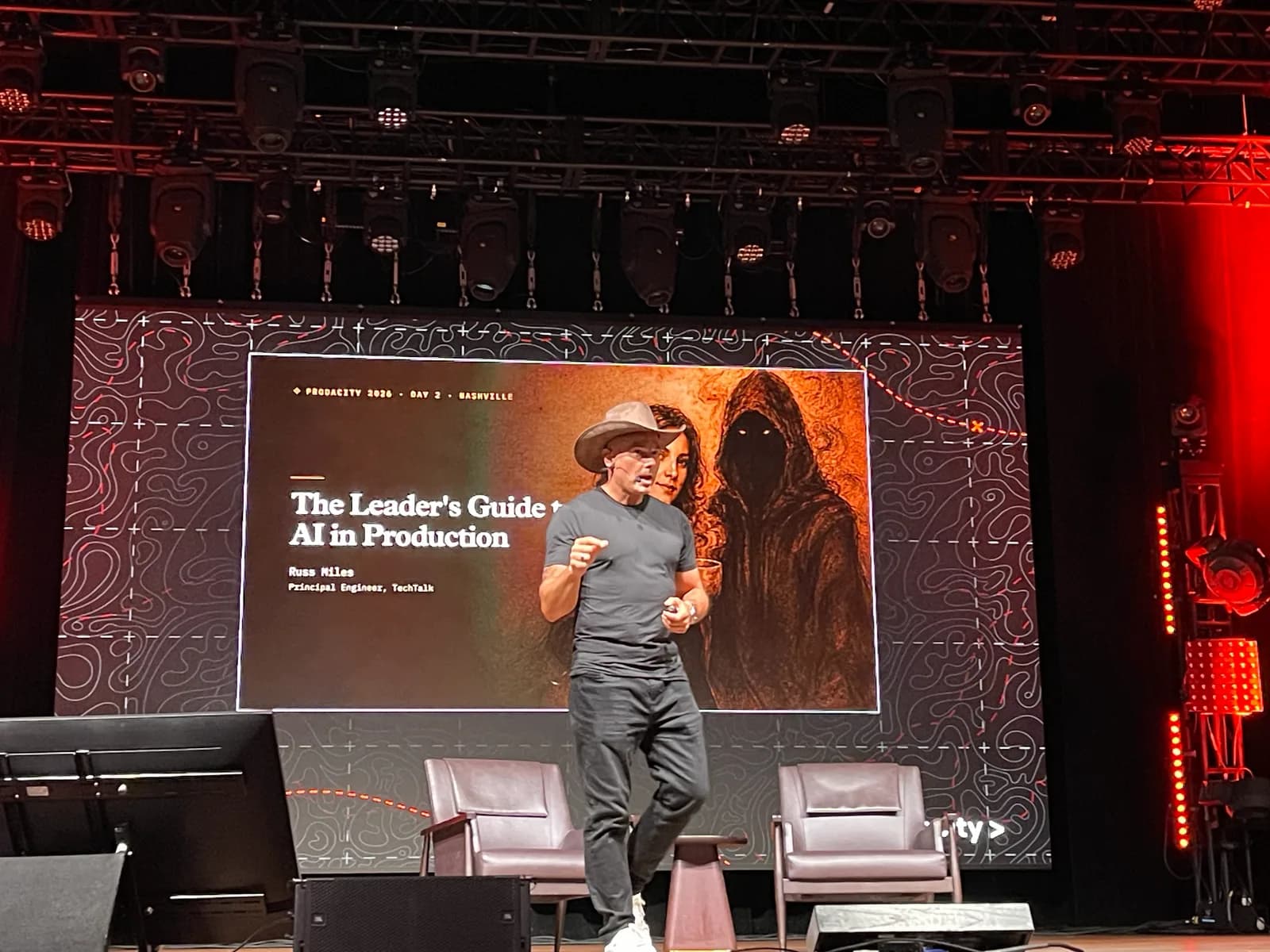 Russ Miles on stage in front of his title slide, The Leader's Guide to AI in Production.