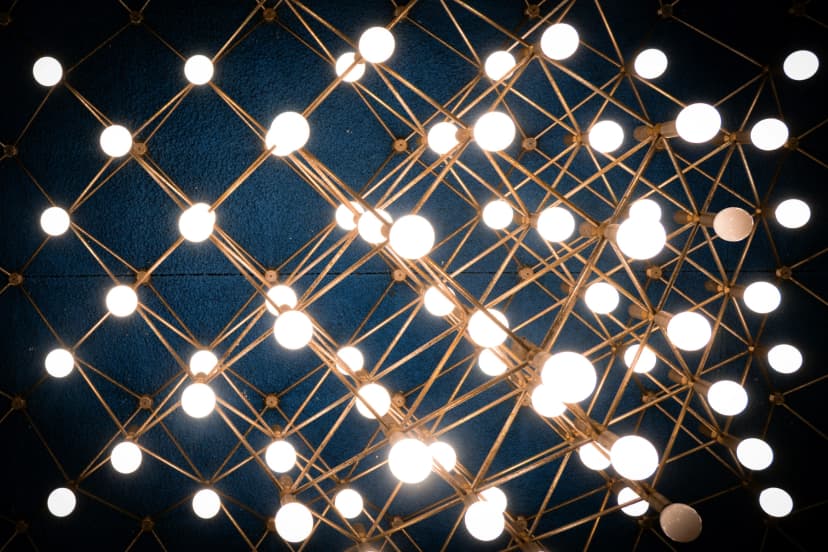 Geometric ceiling light fixture with glowing bulbs against a dark blue ceiling.